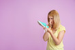 Young woman with stinky shoe on color background. Air freshener