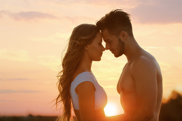 happy young couple in beachwear outdoors at sunset