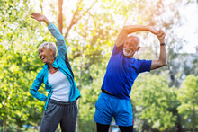 Happy Fit Senior Couple Exercising In Park.