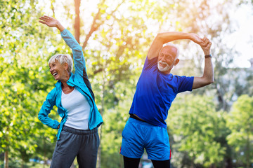 Wall Mural - Happy fit senior couple exercising in park.