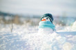Leinwandbild Motiv Little snowman in a cap and a scarf on snow in the winter. Christmas card with a lovely snowman, copy space