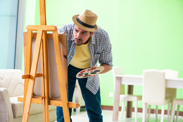 Young male artist working on new painting in his studio