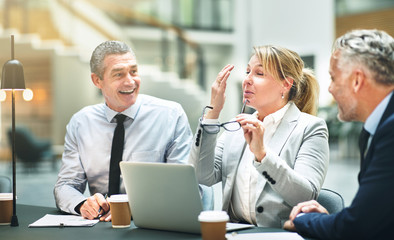 Wall Mural - Mature businesspeople sitting and laughing together at an office