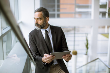 Handsome senior businessman with digital tablet in the modren office