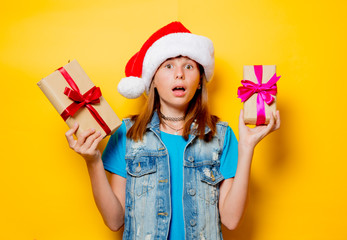 portrait of young teenage girl in Christmas hat with gift box on yellow background