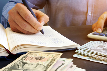 Wall Mural - Man is making financial calculations in the notepad. Bookkeeping.