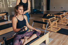 Woman Pulling A Stretch Band  Sitting On Pilates Training Machin