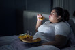 © Creativa Images - Fat woman eating pizza on bed