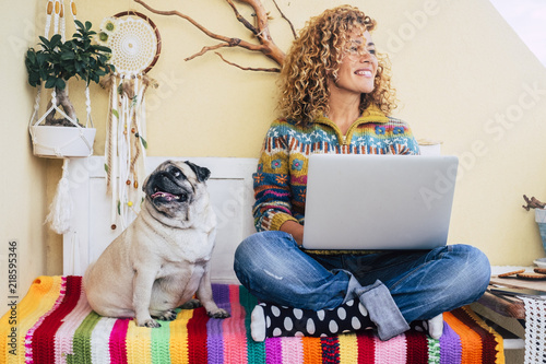 beautiful middle age lady curly hair work with a laptop outdoor at home in the terrace smiling and looking at his side Принти на полотні