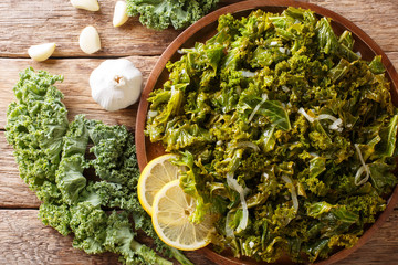 Wall Mural - Vegetarian food: fried kale cabbage with onions and garlic close-up. Horizontal top view