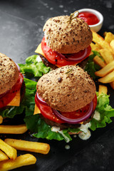 Wall Mural - grilled beef burger with lettuce, greek yogurt souce, beef tomatoes, red onion rings and melted cheese served with potato fries on a rustic counter