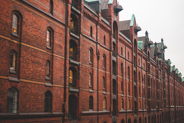 Red bricked buildings of warehouse over the dark canal water in Hafencity, Harbour district in Hamburg, Germany. Mystical gloomy atmosphere