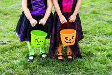 Two Little Girls Hold An Orange And Green Jack O Lantern Trick Or Treat Candy Buckets