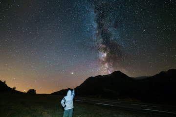Wall Mural - stargazing one person looking at starry sky and milky way at high altitude on the alps. mars planet 