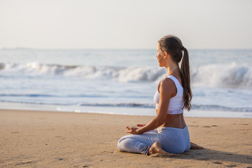 Wall Mural - Caucasian woman practicing yoga at seashore of tropic ocean