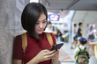 © Mizkit - Beautiful young woman traveler using smartphone at a train station , Transportation and travel lifestyle concept