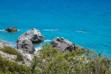 Green scenery - Green bushes on a mountain with a view on big rocks in a sea below.