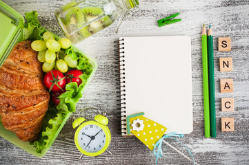 Green lunch box with croissant, salad