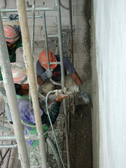 Wall Mural - Construction workers plastering wall using cement plaster at the construction site. They are wearing appropriate safety gear to prevent bad happen.  