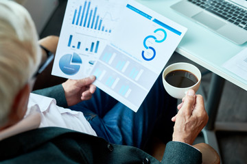 Wall Mural - High angle portrait of unrecognizable senior businessman reading documents while working in cafe during coffee break , copy space