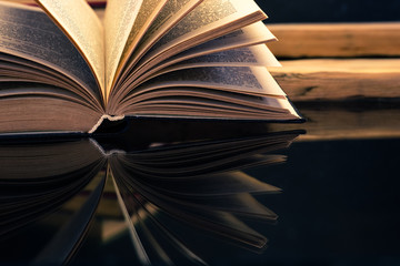 Old book on a oak wooden table. Beautiful dark background.