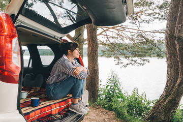 Wall Mural - woman sitting in suv trunk. car travel concept. summer time