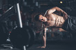 © Yakobchuk Olena - Focus on ripped man doing side plank. He is standing on one hand while putting feet on equipment. Copy space in left side