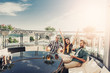 © Yakobchuk Olena - Celebration. Cheerful friends having fun at balcony with cocktails. Beautiful sky, sunlight and city on background