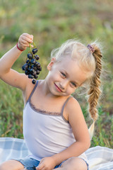 Wall Mural - cute little girl eating grapes in the park