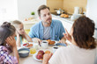 © pressmaster - Young annoyed man rowing with his wife by breakfast in the kitchen with their two daughters near by