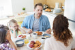© pressmaster - Nervous husband talking to his wife by breakfast with their two little daughters sitting near by