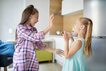 Wall Mural - Two youthful ecstatic girls expressing enjoyment of their play and having fun at home