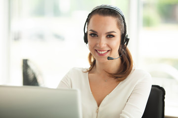 Female customer support operator with headset and smiling.