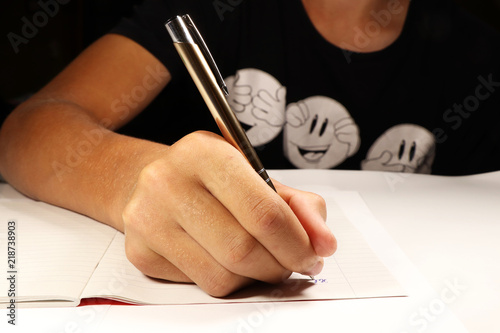 Fotomural A young boy with black t-shirt writing dictation in english lesson
