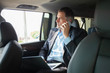 © opolja - Handsome businessman talking with phone sitting with laptop on the backseat of the car.