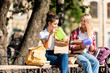 © LIGHTFIELD STUDIOS - happy teen schoolgirls sitting on bench with lunch boxes