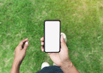 Wall Mural - man holding phone showing blank screen walking on lawn