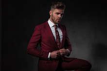 Elegant Man Buttoning His Red Suit While Sitting
