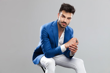 smiling smart casual man sitting and holding palms together