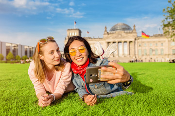 Wall Mural - Two happy woman making selfie on background of Reichstag Bundestag building in Berlin. Travel and love concept in Europe