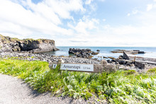 Landscape Trail Hiking View Of Rocky Beach In Hellnar, National Park Snaefellsnes Peninsula, Iceland With Ocean Sea Waves, Green Grass In Summer Day, Cliff, Clouds, Distance Sign To Arnarstapi