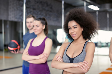 Wall Mural - Sporty girl with group of athletes in gym