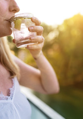 close-up of blond woman outdoors on summer day drinking iced drink