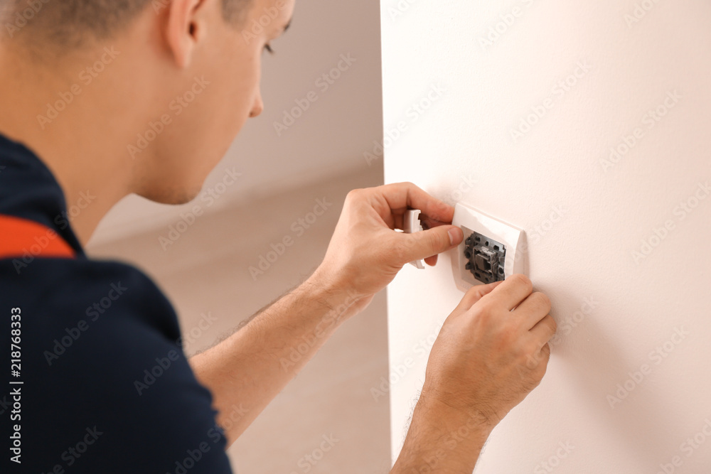 Electrician repairing wall switch indoors