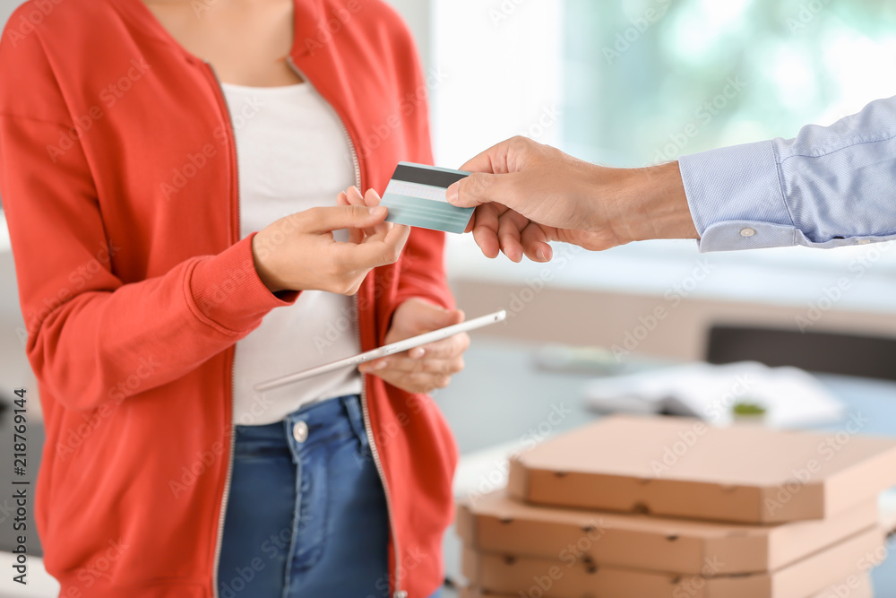Man paying for pizza with credit card indoors, closeup. Food delivery service