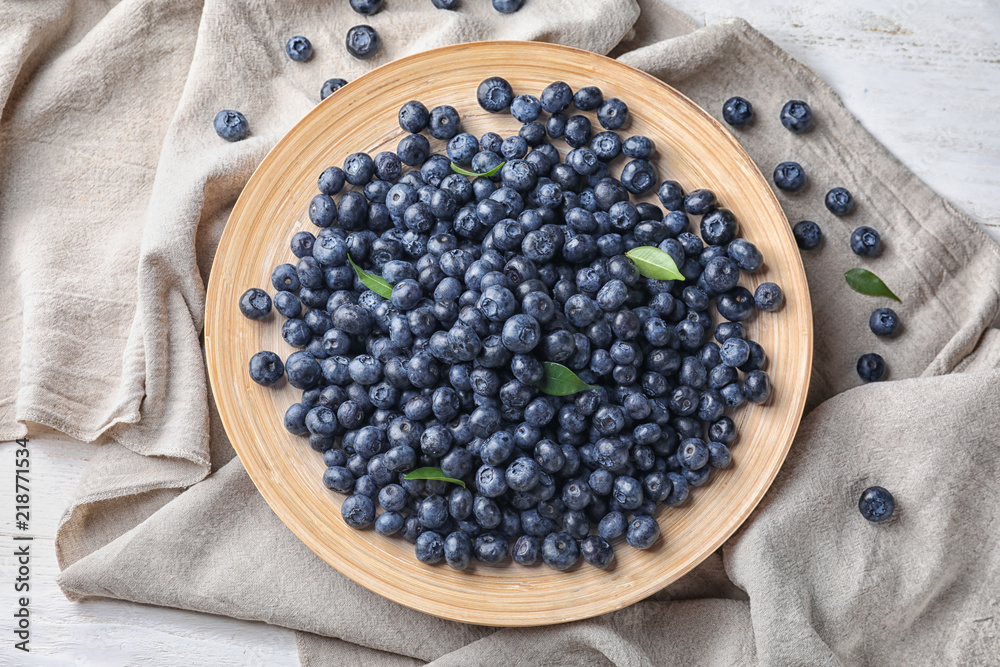 Plate with ripe blueberries on table