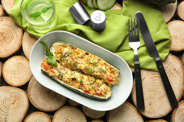 Plate with quinoa stuffed zucchini boats on wooden background