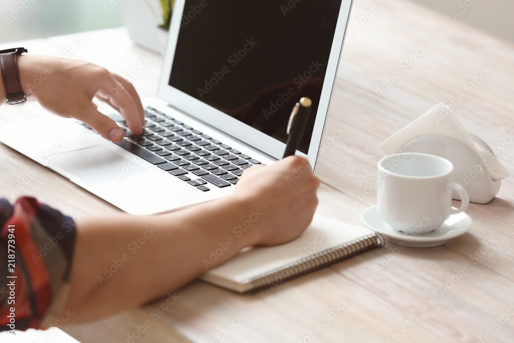 Young freelancer working on laptop in cafe, closeup