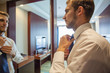 © opolja - People, business,fashion and clothing concept - close up of man in shirt dressing up and adjusting tie on neck at home.