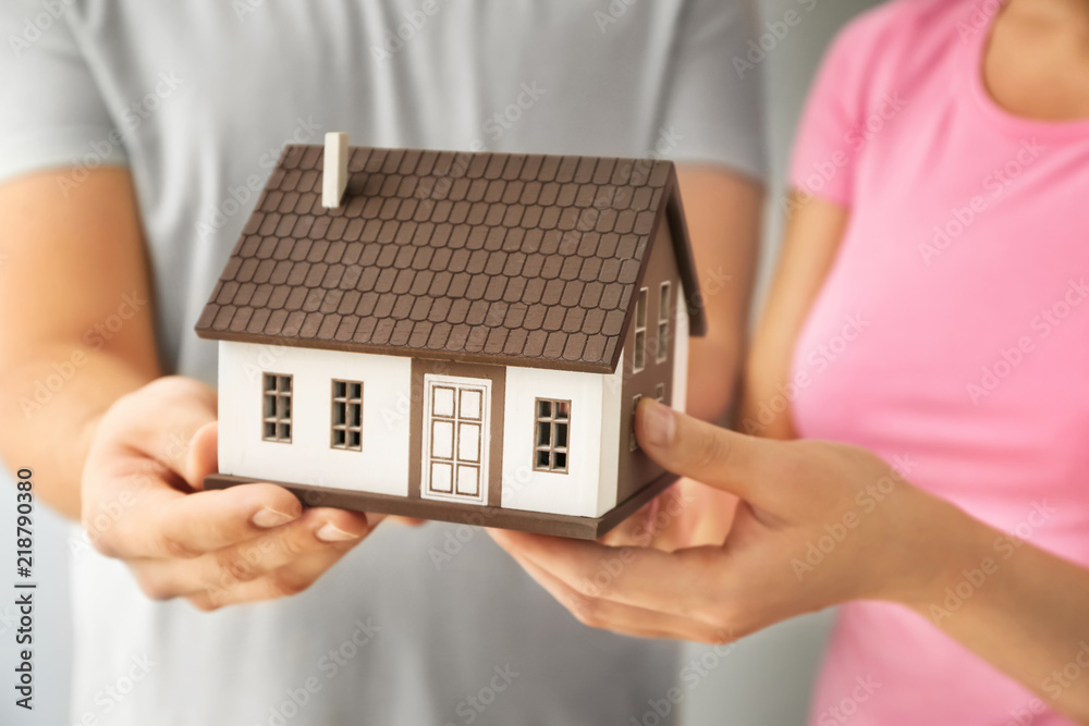 Young couple holding house model, closeup. mortgage concept